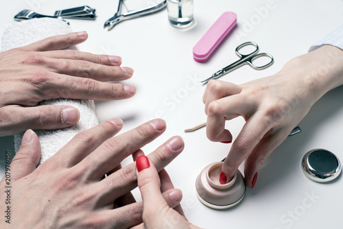 Men s manicure. woman beautician applies moisturizer to dry male hands