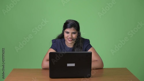 Young overweight beautiful Indian businesswoman against green background