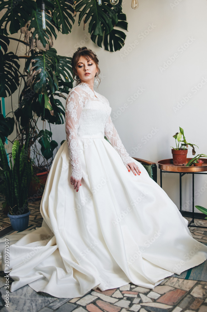 Fototapeta premium pretty woman in a wedding dress in the depressions of living plants.