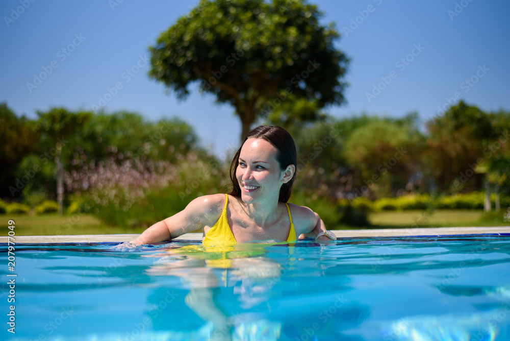 Portrait of a cheerful smiling girl in the hotel pool on vacation
