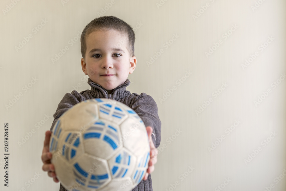 Cheerful boy with a soccer ball in his hand. Light background. European appearance. copy space Cheerful boy with a soccer ball in his hand. Light background. European appearance. copy space