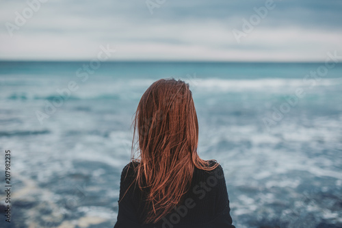 Girl with long hair facing the sea