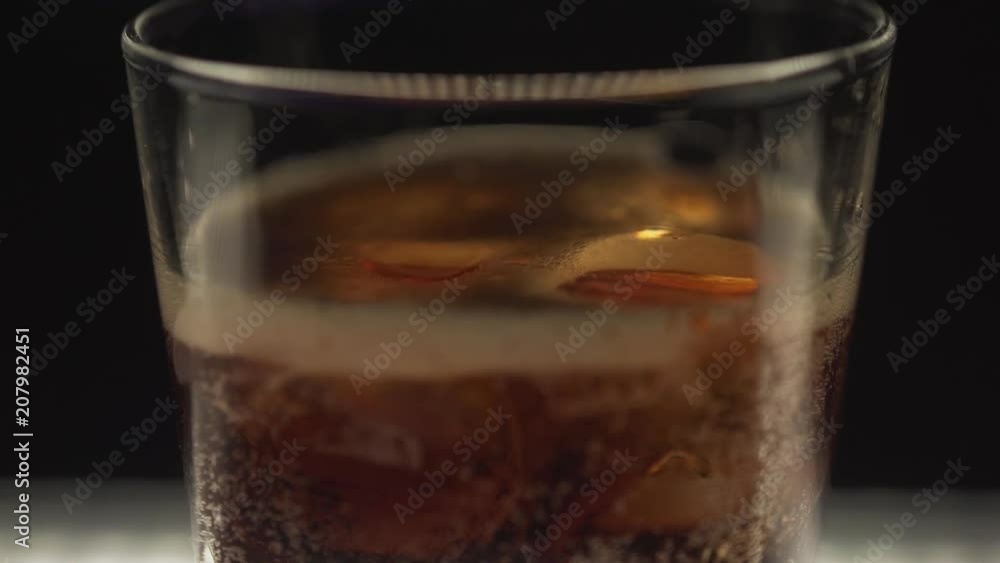 Coca Cola poured into a glass with ice. The soda is poured into a glass with ice. Coca Cola poured into a glass with ice. The soda is poured into a glass with ice.