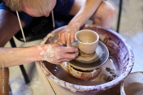 Man making a pot of clay. Pottery wheel. Workshop of art therapy. A dirty male hands. Modeling of a ceramic cup