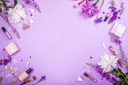 Set of cosmetics  brushes and jewellery with fresh flowers on purple background. Summer sale. Shopping