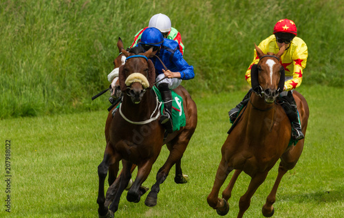 Lead race horses and jockeys racing down the track