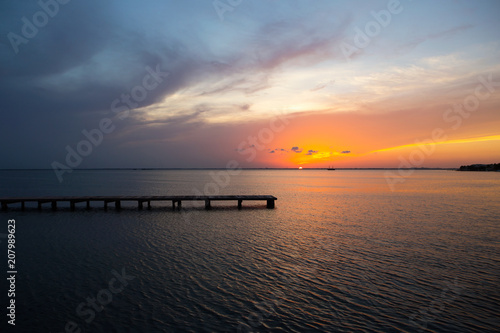 A colorful sunset over a small pier at the bay of Cancun, Mexico