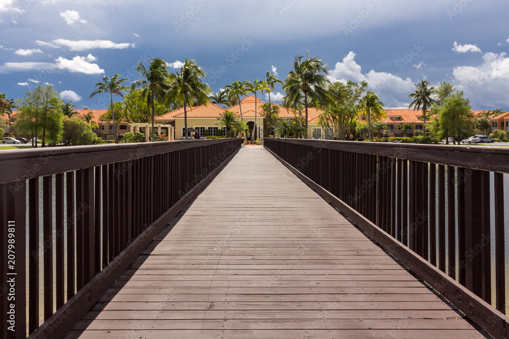 Puente de madera con casa y palmeras al final. punto de fuga