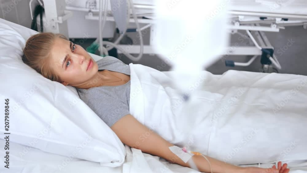 Young female patient lying in a hospital room. Sad and upset woman thinking about life in a modern clinic Young female patient lying in a hospital room. Sad and upset woman thinking about life in a modern clinic
