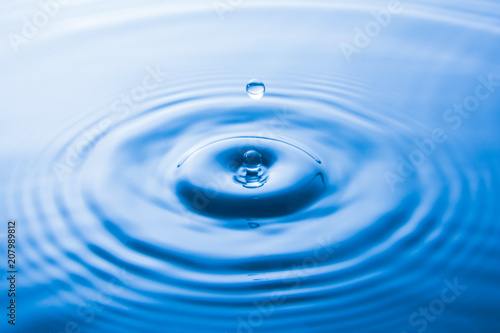 Water drop falling into water make waves. Water splash or water drop background.