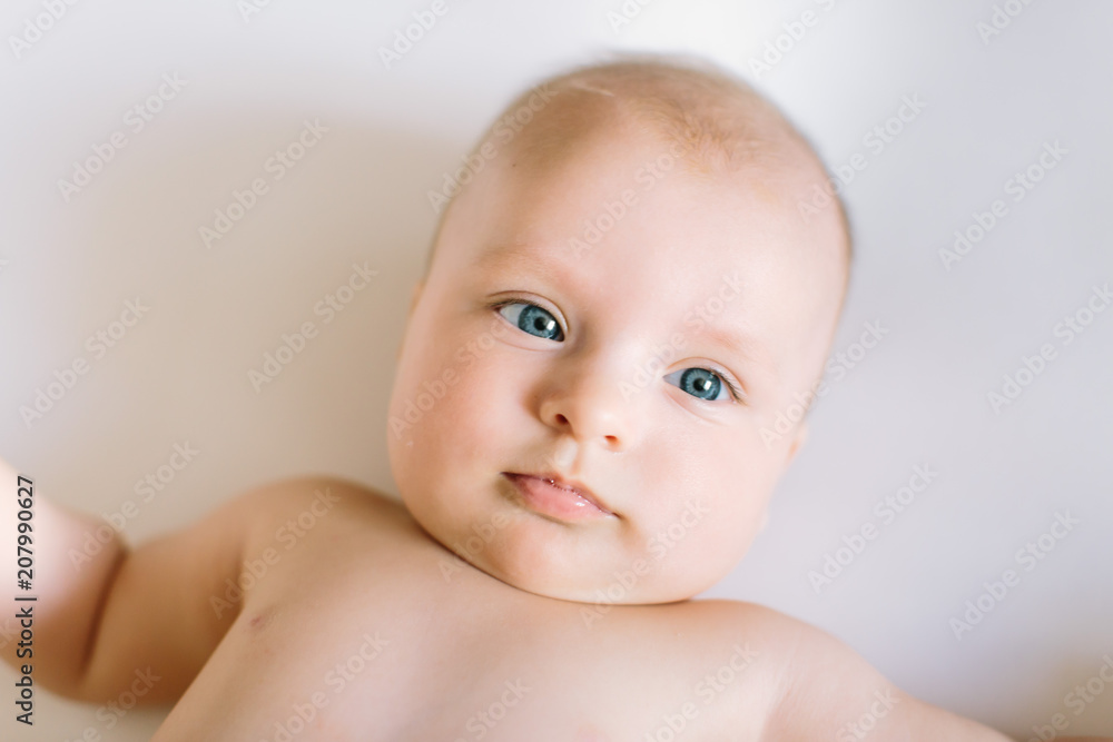 Newborn baby girl posed in a bowl on her back, on blanket of fur, smiling looking at camera Newborn baby girl posed in a bowl on her back, on blanket of fur, smiling looking at camera
