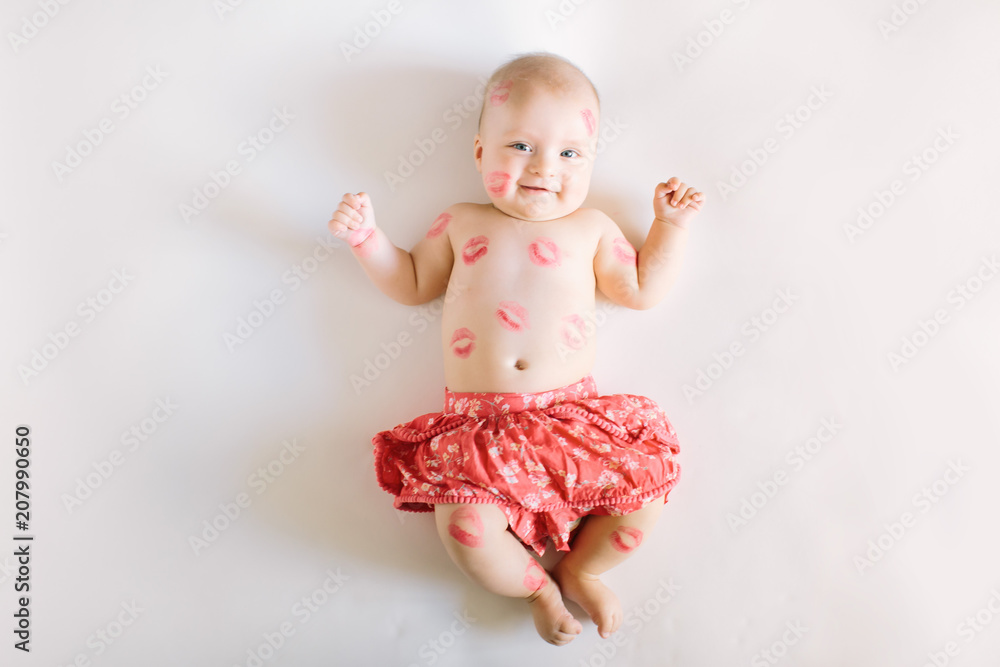 Image of adorable child with red kisses on the skin, happy baby boy sitting down in the studio and isolated on white background, little love angel, romantic holiday, Valentines day concept Image of adorable child with red kisses on the skin, happy baby boy sitting down in the studio and isolated on white background, little love angel, romantic holiday, Valentines day concept