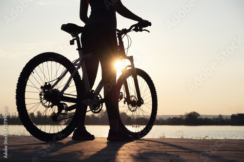 Fototapeta Naklejka Na Ścianę i Meble -  Silhouette of a girl near sea on the bike. Sport and active life concept