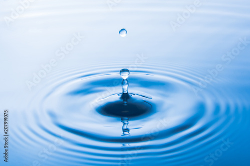 Water drop falling into water make waves. Water splash or water drop background.