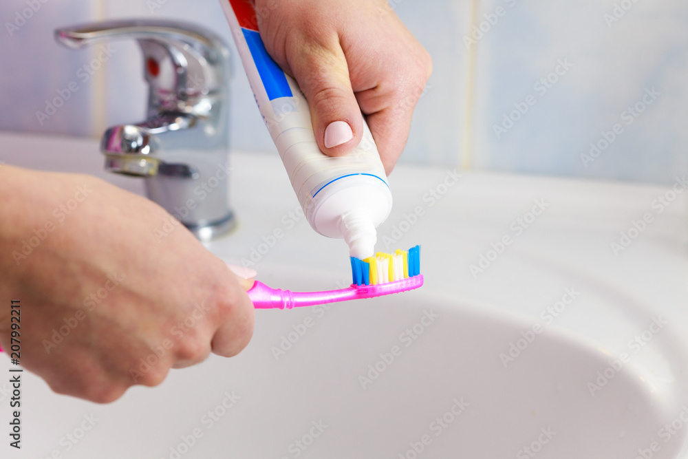 Hand applied toothpaste on toothbrush Hand applied toothpaste on toothbrush