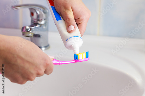 Hand applied toothpaste on toothbrush © Voyagerix