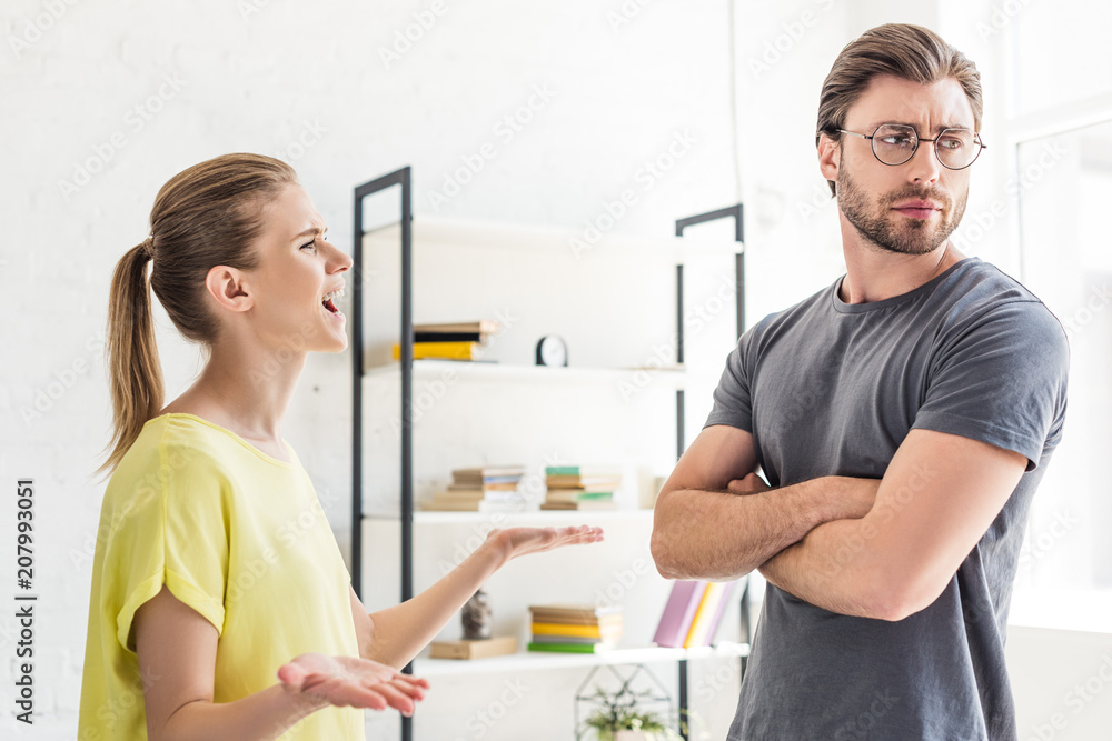 Fototapeta premium side view of woman yelling at boyfriend while she standing with crossed hands