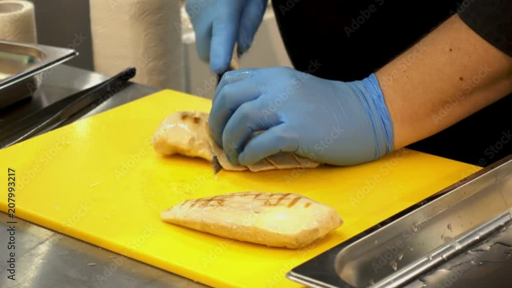 Hands of the cook cut pieces of fried chicken on a yellow cutting board. HD video Hands of the cook cut pieces of fried chicken on a yellow cutting board. HD video