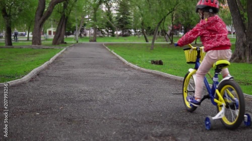 Wallpaper Mural A happy little girl learns to ride a bicycle, she keeps her balance and speed on her bike in the park, slow-motion shooting. Torontodigital.ca
