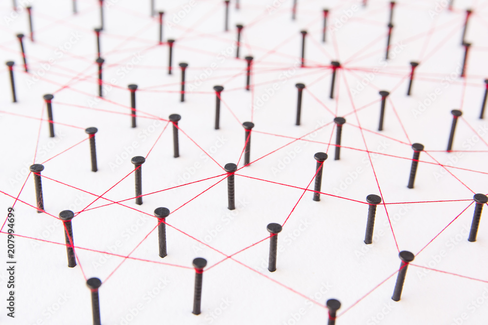 Linking entities, social media, Communications Network, The connection between the two networks. Network simulation on white paper linked together created by black nail and red thread Linking entities, social media, Communications Network, The connection between the two networks. Network simulation on white paper linked together created by black nail and red thread