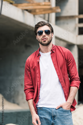 young stylish man in sunglasses at construction building