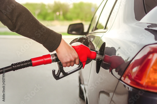 Man hand is inserting a fuel nozzle in a gas tank. Car gas station. Refueling concept.