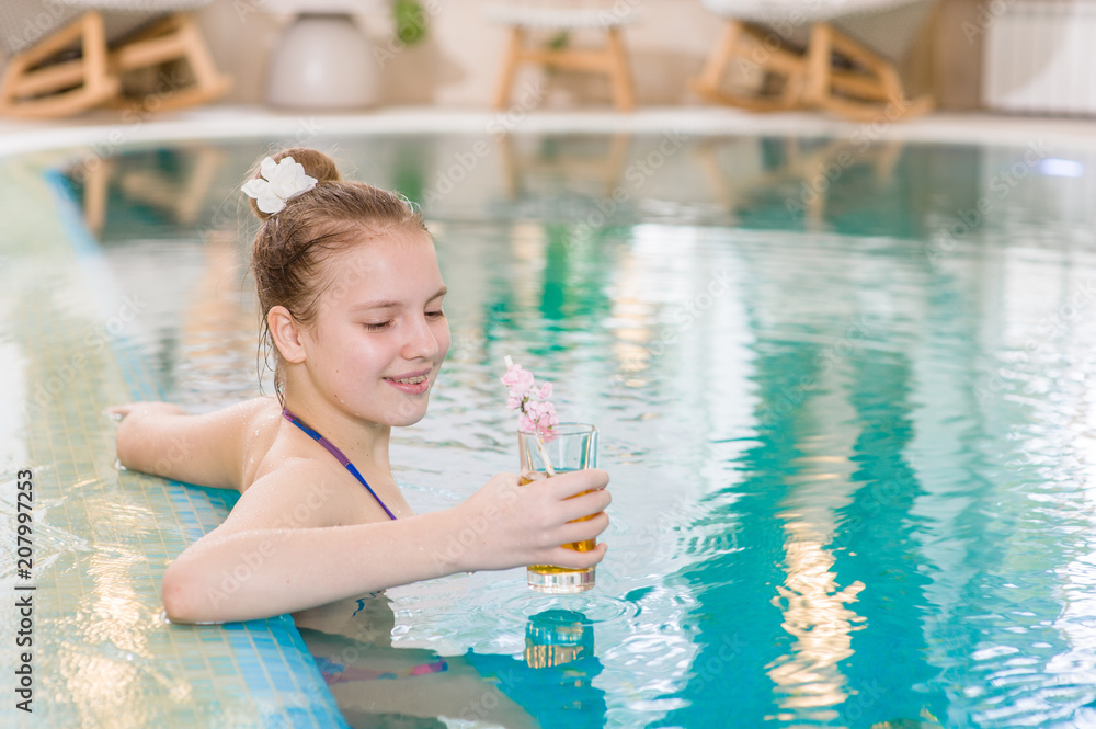 Naklejka premium Happy teen girl in the pool holding a glass of cocktail