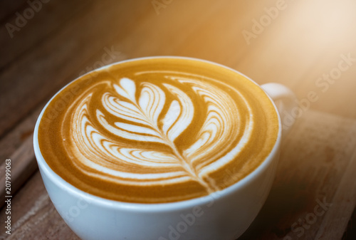 A white cup of coffee latte or cappuccino art on wood table