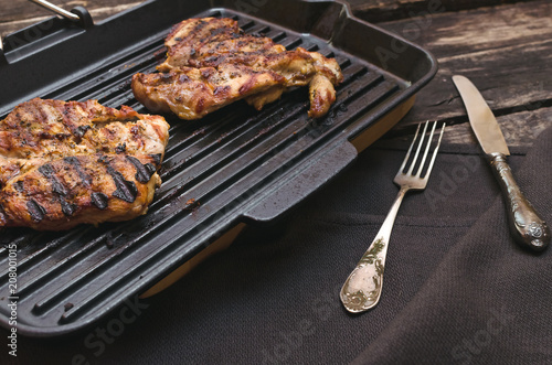 Grilled turkey meat on the pan on the wooden background.