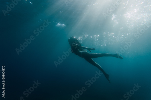 Wide shot of a woman swimming underwater photo