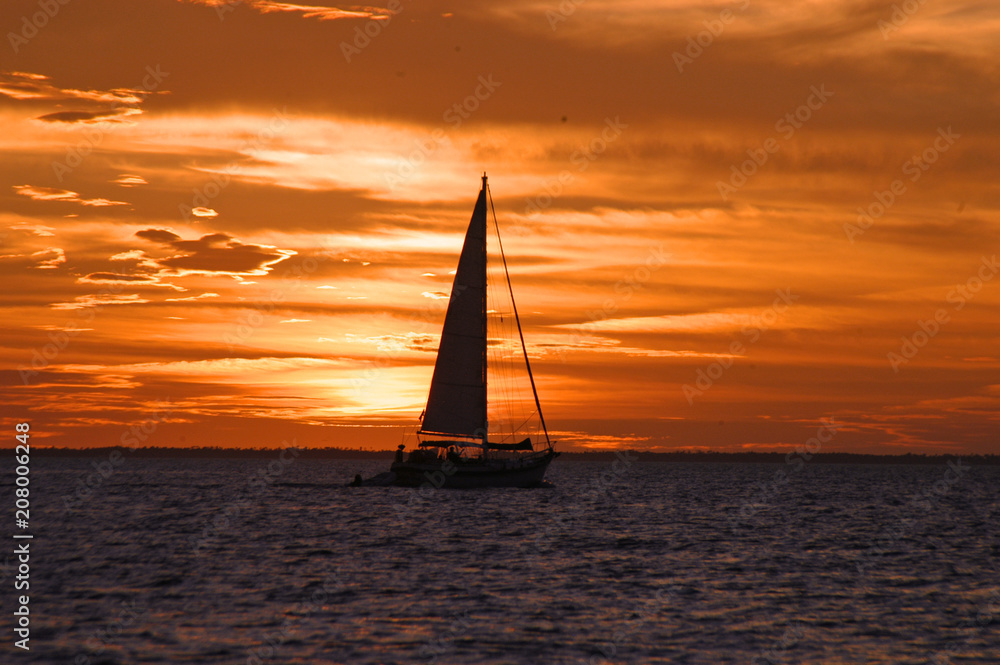 Fototapeta premium Sailboat silhouette and red sky at night