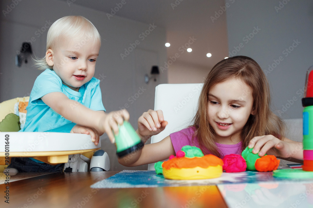 Fototapeta premium Two happy children Blond boy and girl playing sitting at table at home
