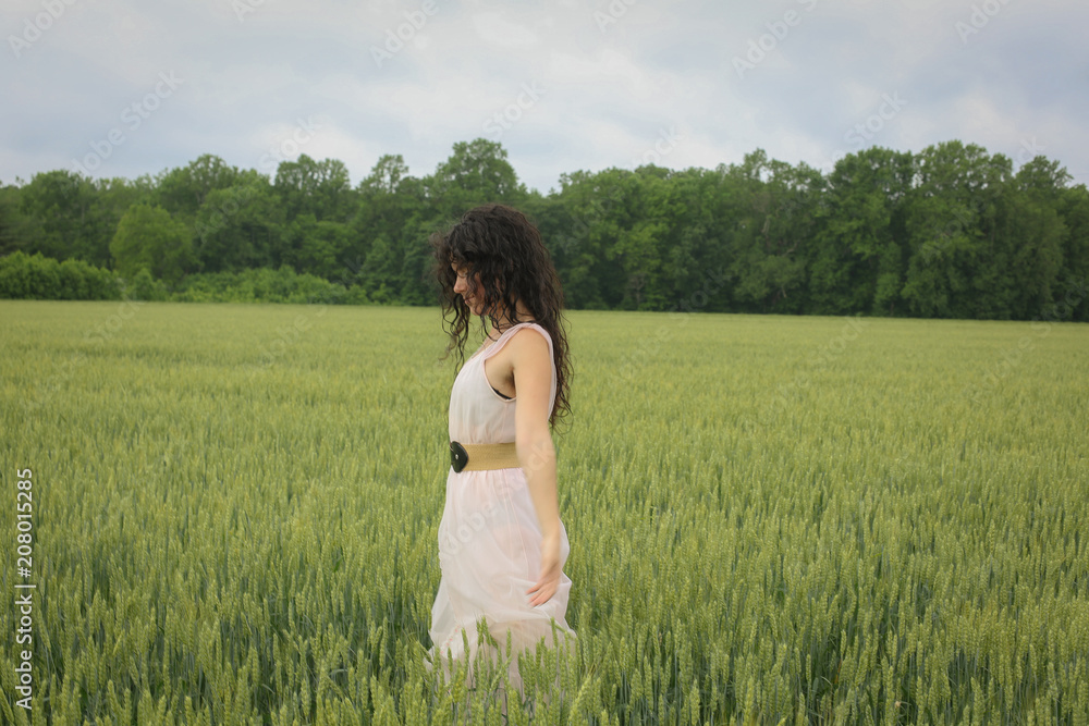 Woman Female Model in a Wheat Field Surrounded by Trees in Spring or Summer Wearing a Pink Flowing Dress Woman Female Model in a Wheat Field Surrounded by Trees in Spring or Summer Wearing a Pink Flowing Dress