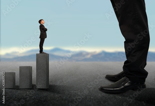 Business concept.Tiny businessman looking up on giant legs of another businessman.Career growth and opportunities.a small business looking up a Big business