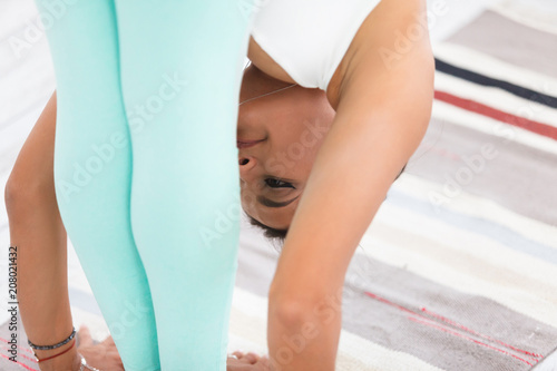 Balance and pacification. Young slender woman doing a yoga exercise - Padangushthasana in a modern home interior. close-up