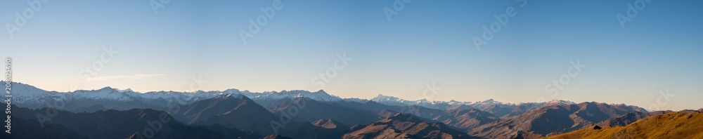 Panorama view of a beautiful landscape of a yellow grassland blue sky and Alps mountain at sunset.
