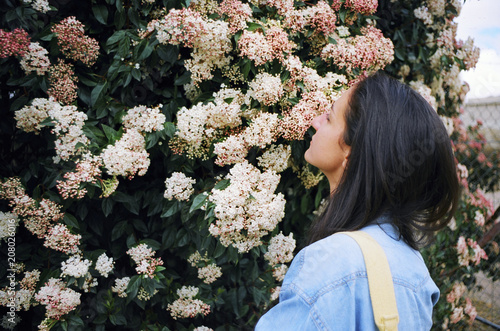 Attractive young woman stopping to smell the flowers photo