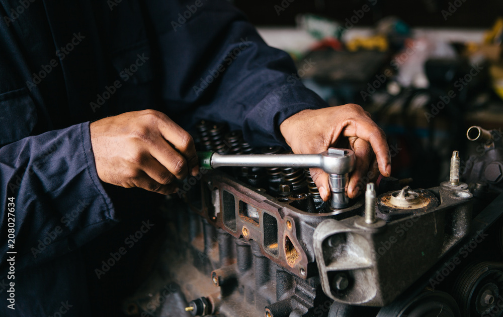 Mechanic fixing an engine for a head gasket repair in a garage. Mechanic fixing an engine for a head gasket repair in a garage.
