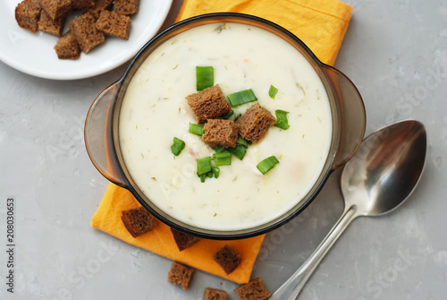 Cream Soup with Chicken Meat and Bread Crackers Croutons Orange Napkin Gray Textured Background