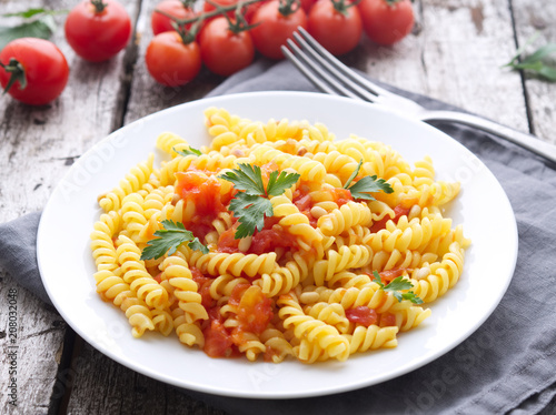 Pasta fusilli with tomatoes with parsley on a old rustic gray wooden background, low-calorie diet, side view