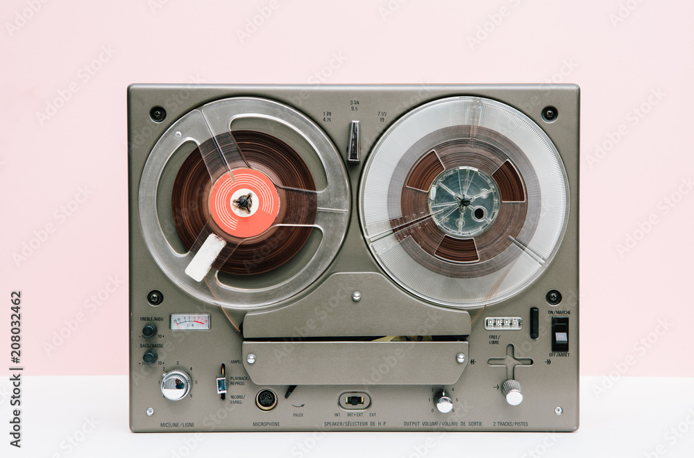 Vintage reel to reel in front of a pink background
