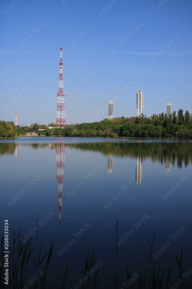 Obraz premium Image of a television tower on the shore of a pond.