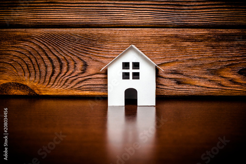  The symbol of the house stands on a brown wooden background 