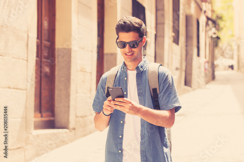 happy young student male texting on his smart phone in modern city