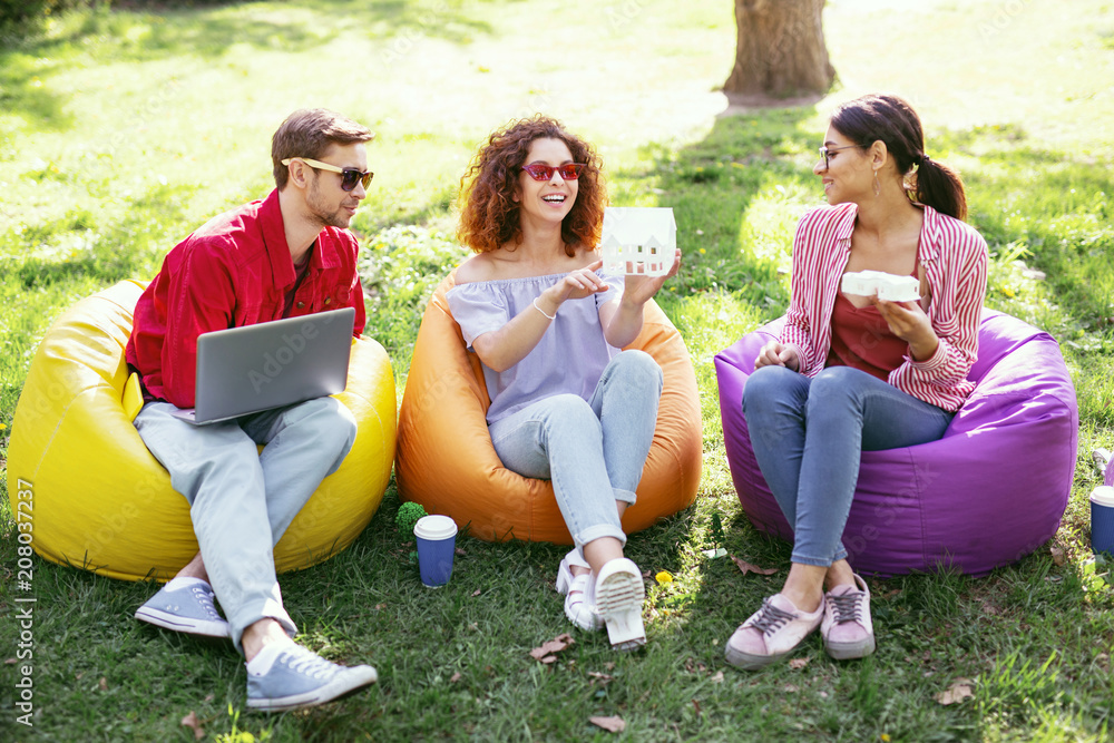 Our future project. Cheerful ambitious colleagues sitting in the open air and working on the project Our future project. Cheerful ambitious colleagues sitting in the open air and working on the project