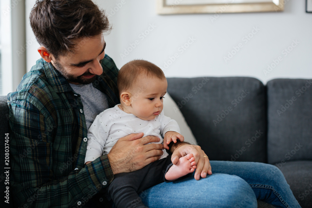 Young father sitting on couch with his baby boy. Young father sitting on couch with his baby boy.