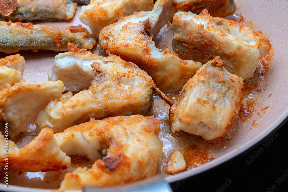 Pieces of fish fried in a hot pan Pieces of fish fried in a hot pan