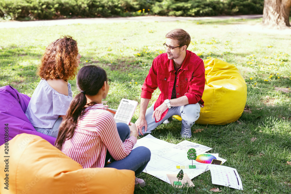 Great mood. Handsome determined man talking with his co-workers while working in the open air Great mood. Handsome determined man talking with his co-workers while working in the open air