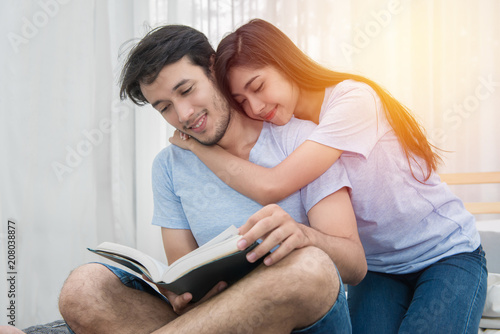 young loving couple reading a book on bedroom at home