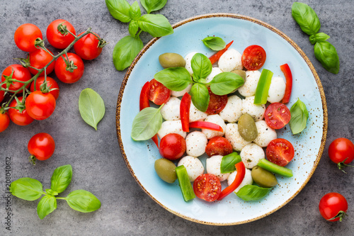 Delicious caprese salad with ripe cherry tomatoes and mini mozzarella cheese balls with fresh basil leaves.